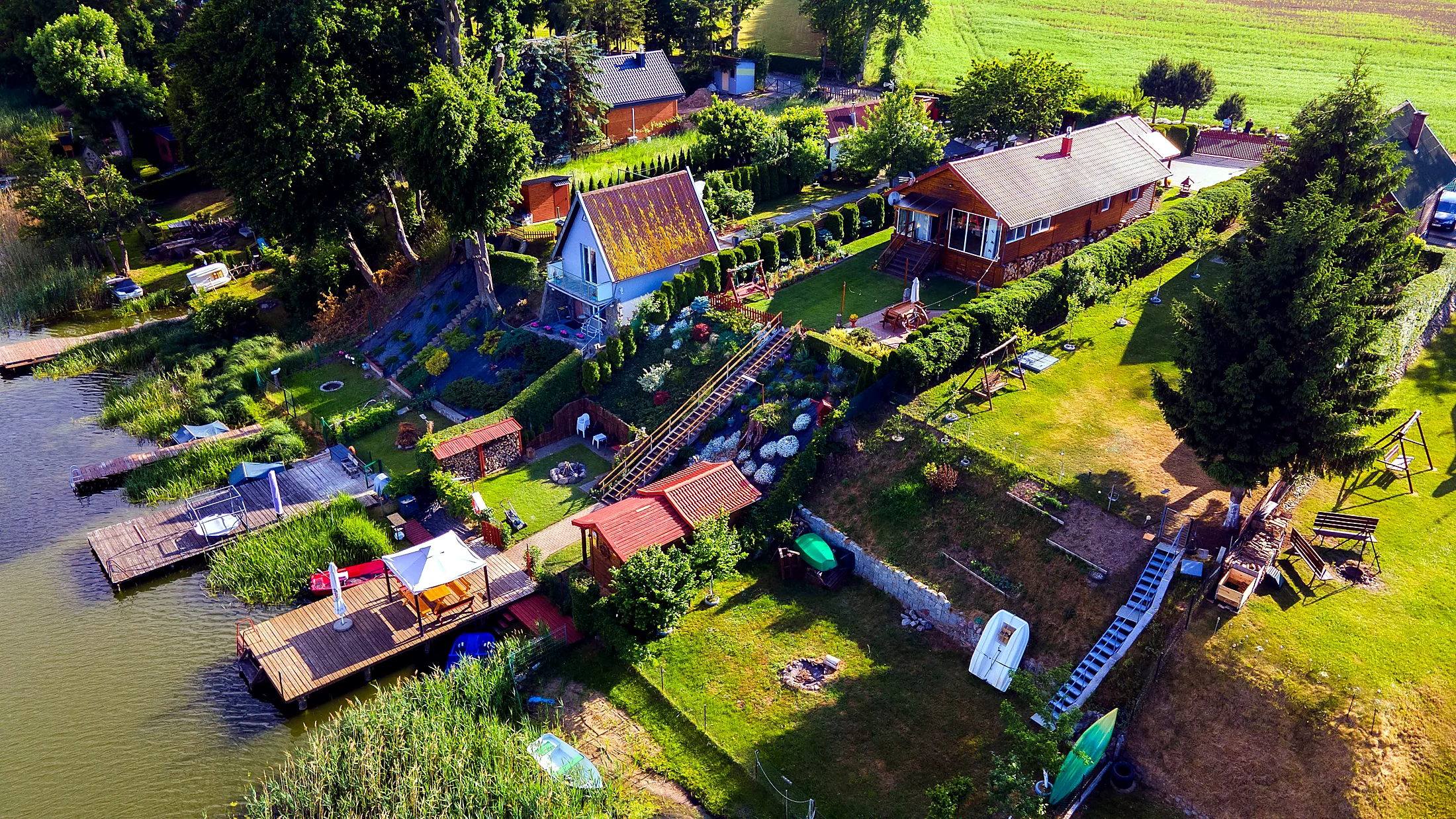 Widok z góry na dom, ogród, pomost, sprzęt wodny i Jezioro Pozorty